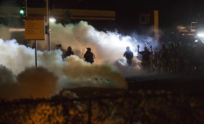 Riot police clear a street with smoke bombs while clashing with demonstrators in Ferguson, Missouri