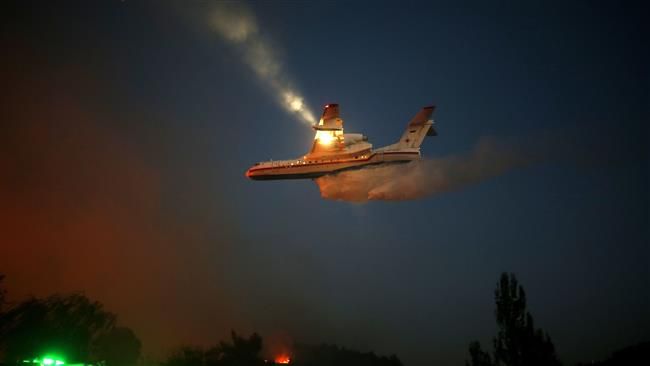  An Israeli firefighter plane helps extinguish a fire in Haifa on November 24, 2016. (Photo by AFP)